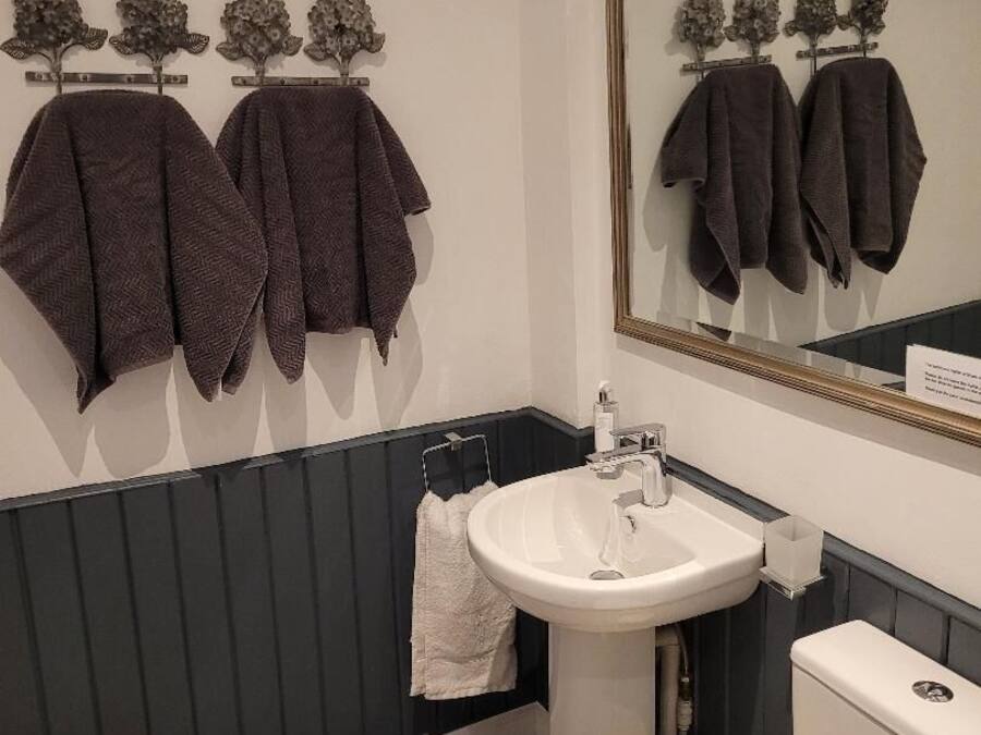 A bathroom with a white sink, a mirror, and towels hanging on a rack.