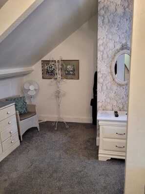 A bedroom with a bed, dresser, vanity, mirror, and a fan. - The Bridges B&B (Morpeth)