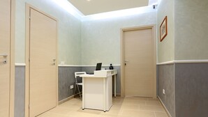 Una habitación limpia y bien iluminada con una mesa de recepción, una silla y una puerta.