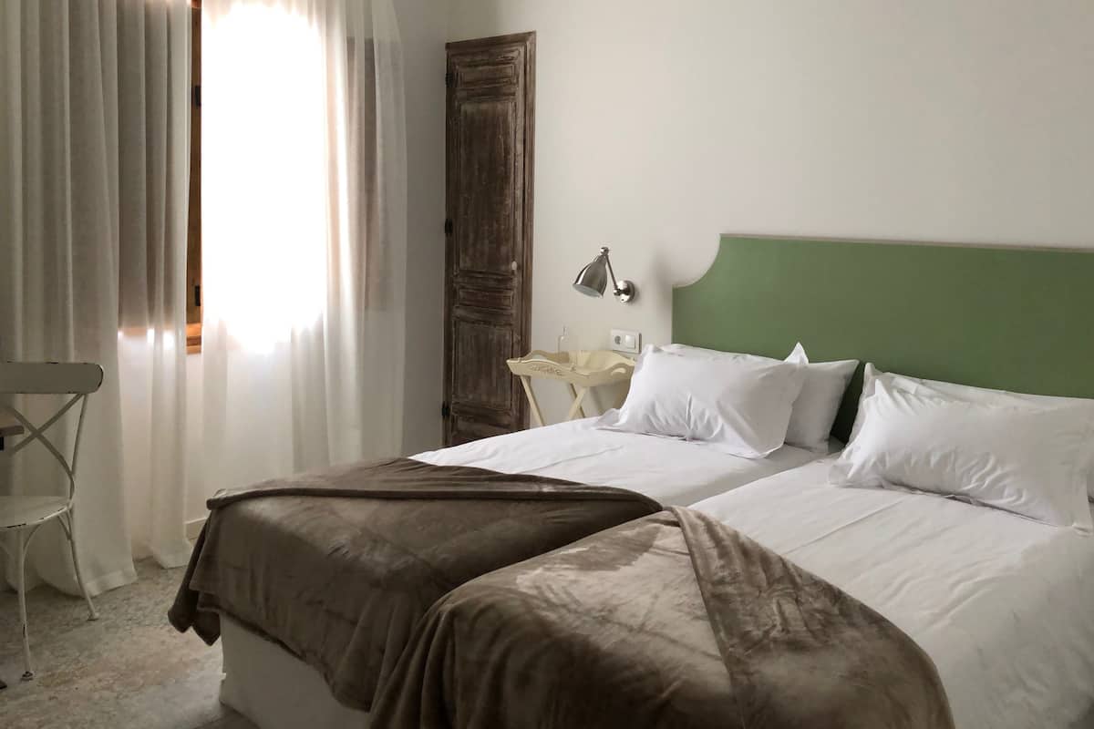 A hotel room with a bed, a nightstand, a lamp, and a chair.
