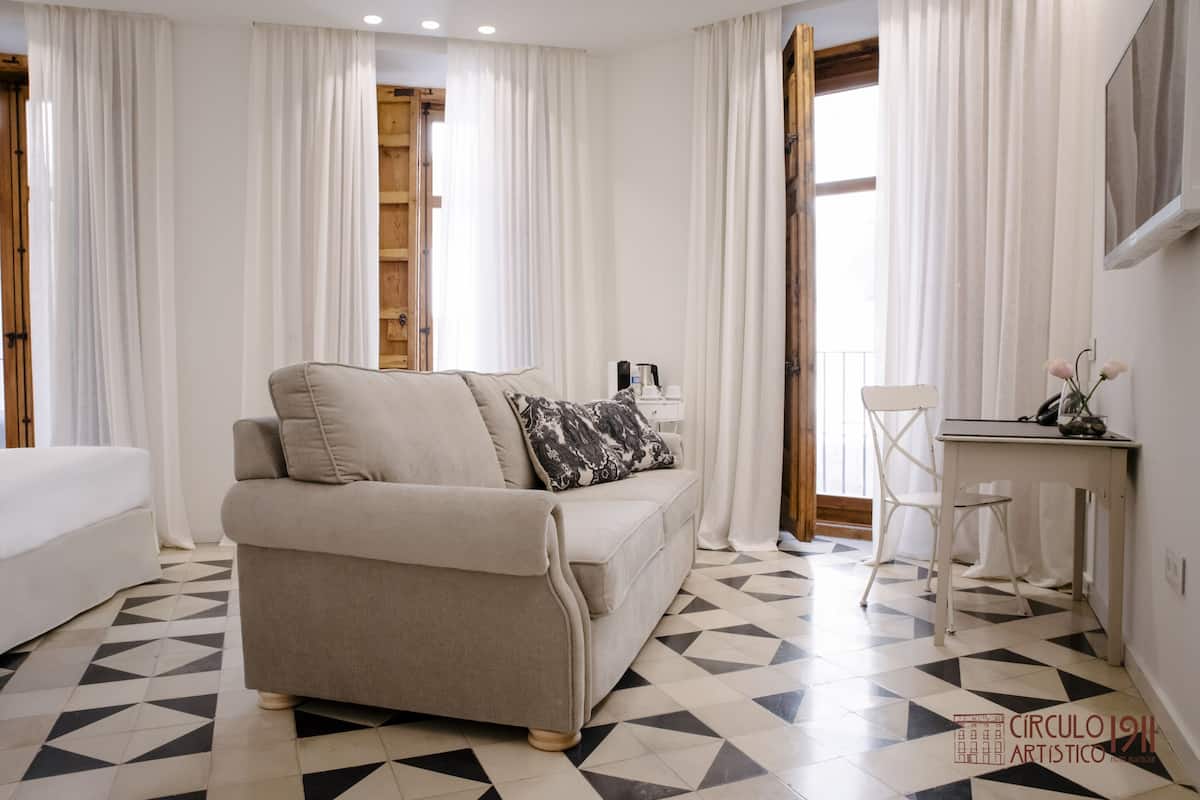 A modern room with a beige sofa, a small white desk, and a chair.