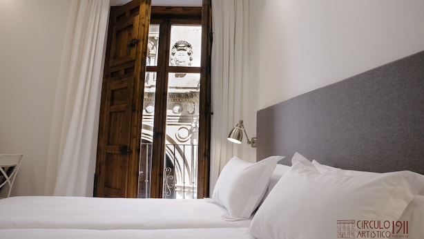 Une chambre d’hôtel avec un lit, une porte en bois et une vue sur un bâtiment à l’architecture richement décorée.