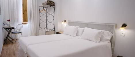 Habitació d'hotel amb un llit gran, una cadira, escriptori amb una làmpada i un penjallabecs.