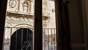 Une façade d’immeuble présentant des éléments architecturaux classiques, notamment une statue, des moulures décoratives et une grande entrée en arc de cercle.