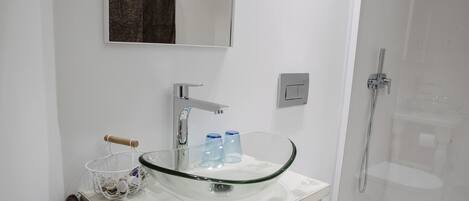 A modern bathroom with a glass sink, a towel rack, and a shower.