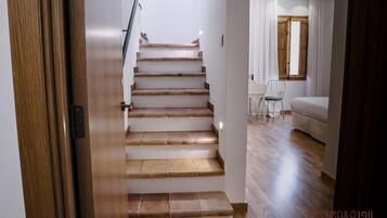 Una escalera de madera conduce a una habitación con una cama y una silla.