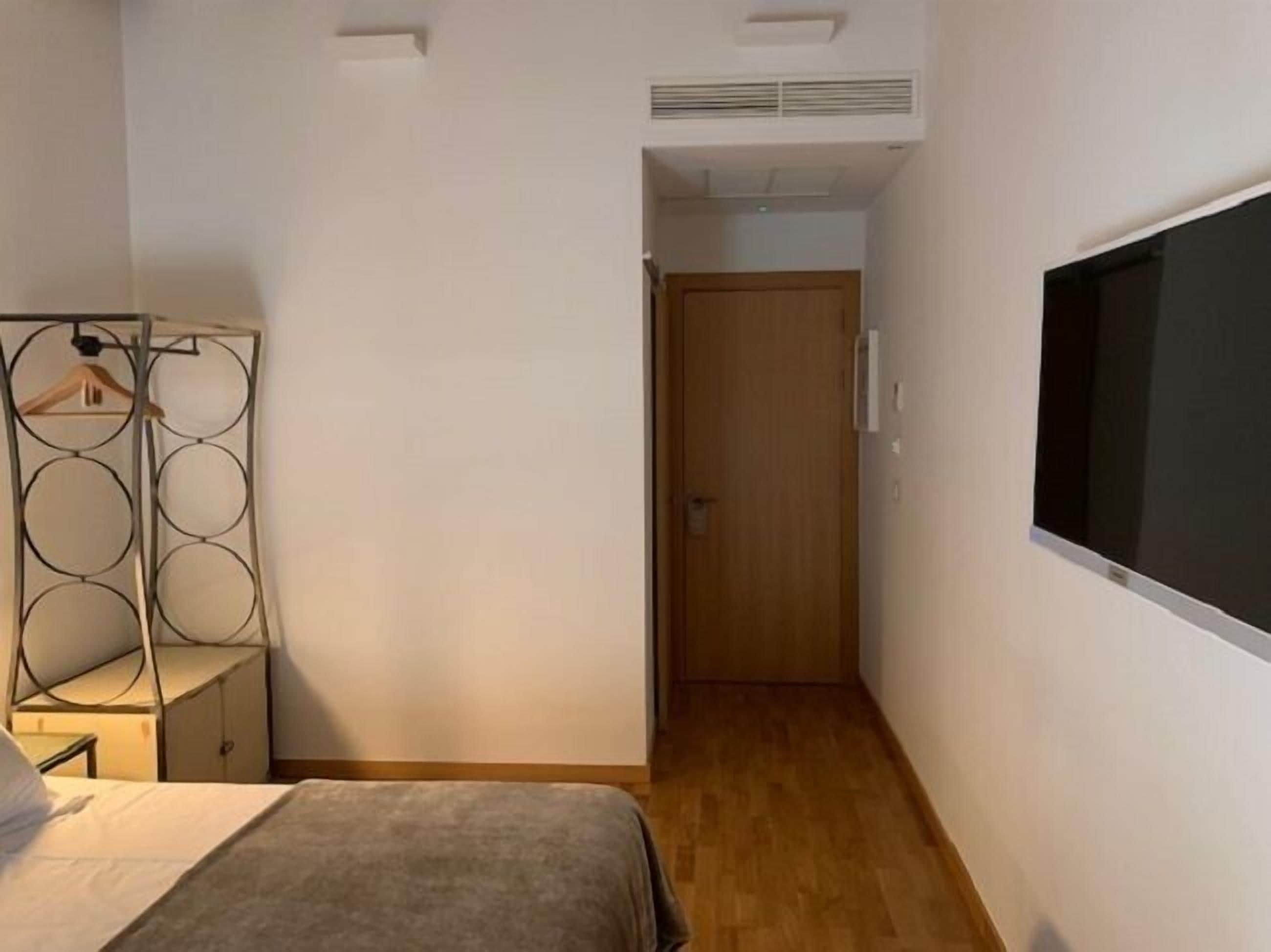 Un dormitorio con cama, armario, televisor y puerta que da a otra habitación.