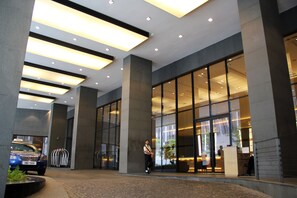 A modern hotel lobby with large glass doors, a reception desk, and a blue car parked outside. - 188 Private Suites by Subhome (Kuala Lumpur)