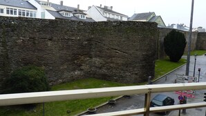 Eine Steinmauer mit einer Rasenfläche und einer Straße mit Wegweisern.