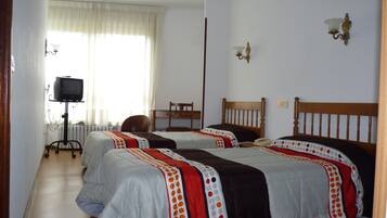 Habitación de hotel con dos camas, televisión y una silla.