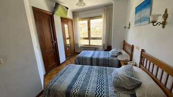 Un dormitorio con dos camas, una ventana con cortinas, un cuadro en la pared y un ventilador de techo.