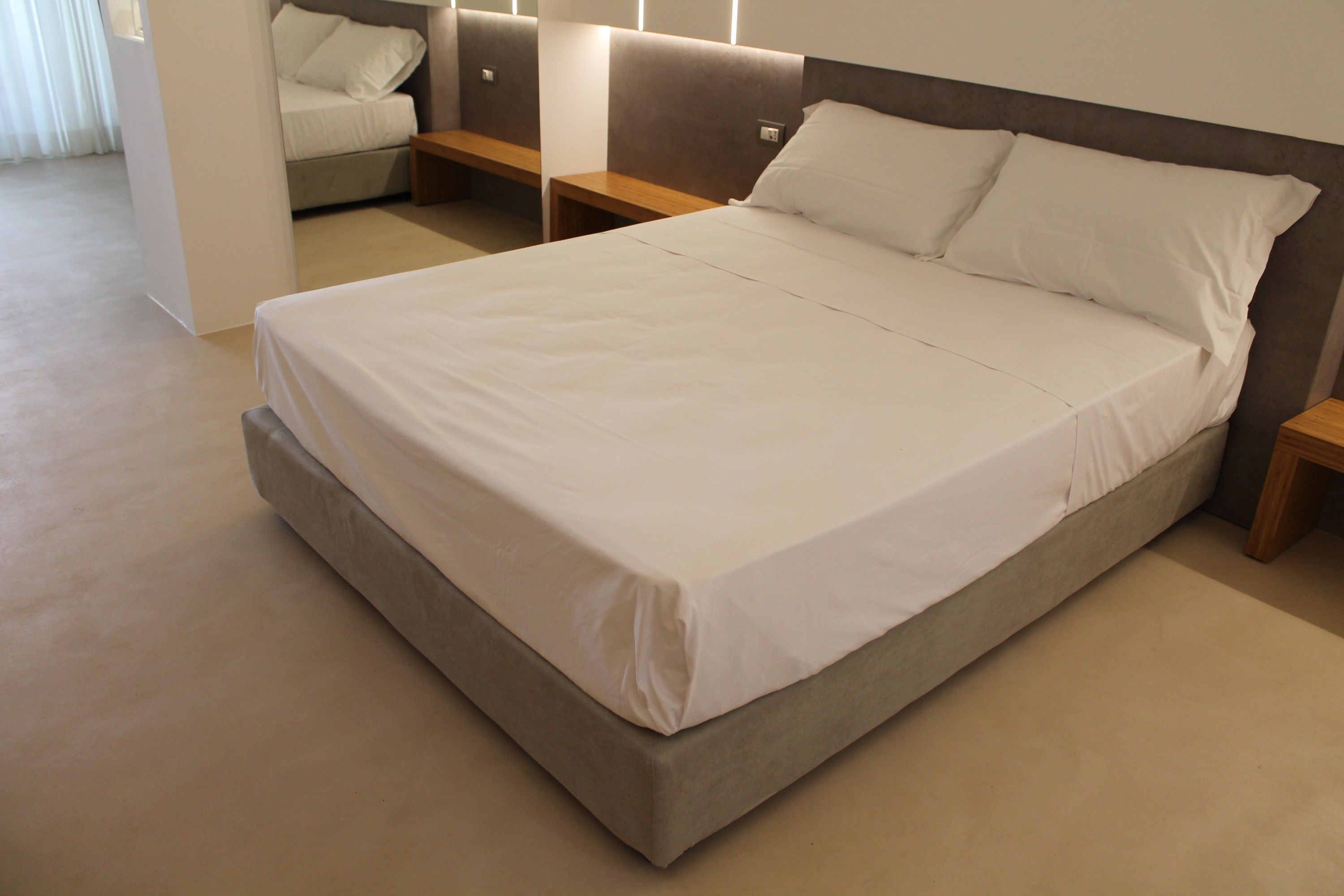 A large bed with a wooden headboard, a bedside table, and a bench.