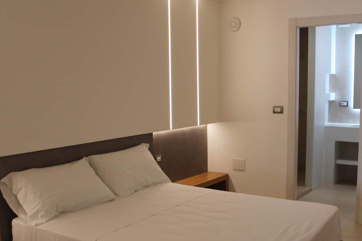 A modern bedroom with a large bed, bedside tables, and a built-in bench.