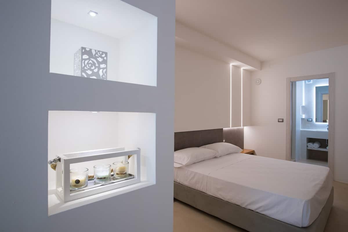 A modern bedroom with a bed, bedside table, and a mirror.