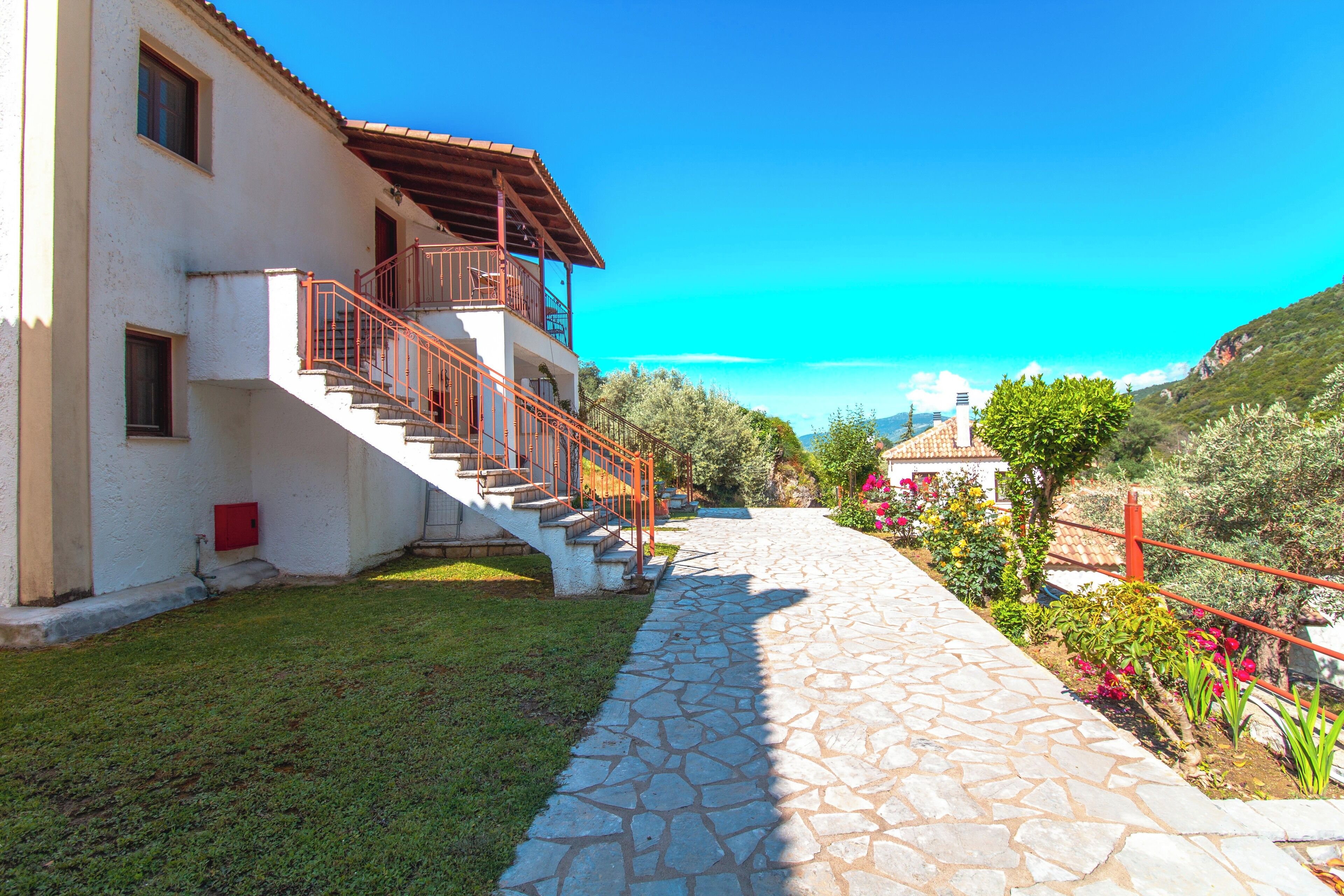 Una casa de dos pisos con un sendero de piedra que conduce a una escalera de madera.