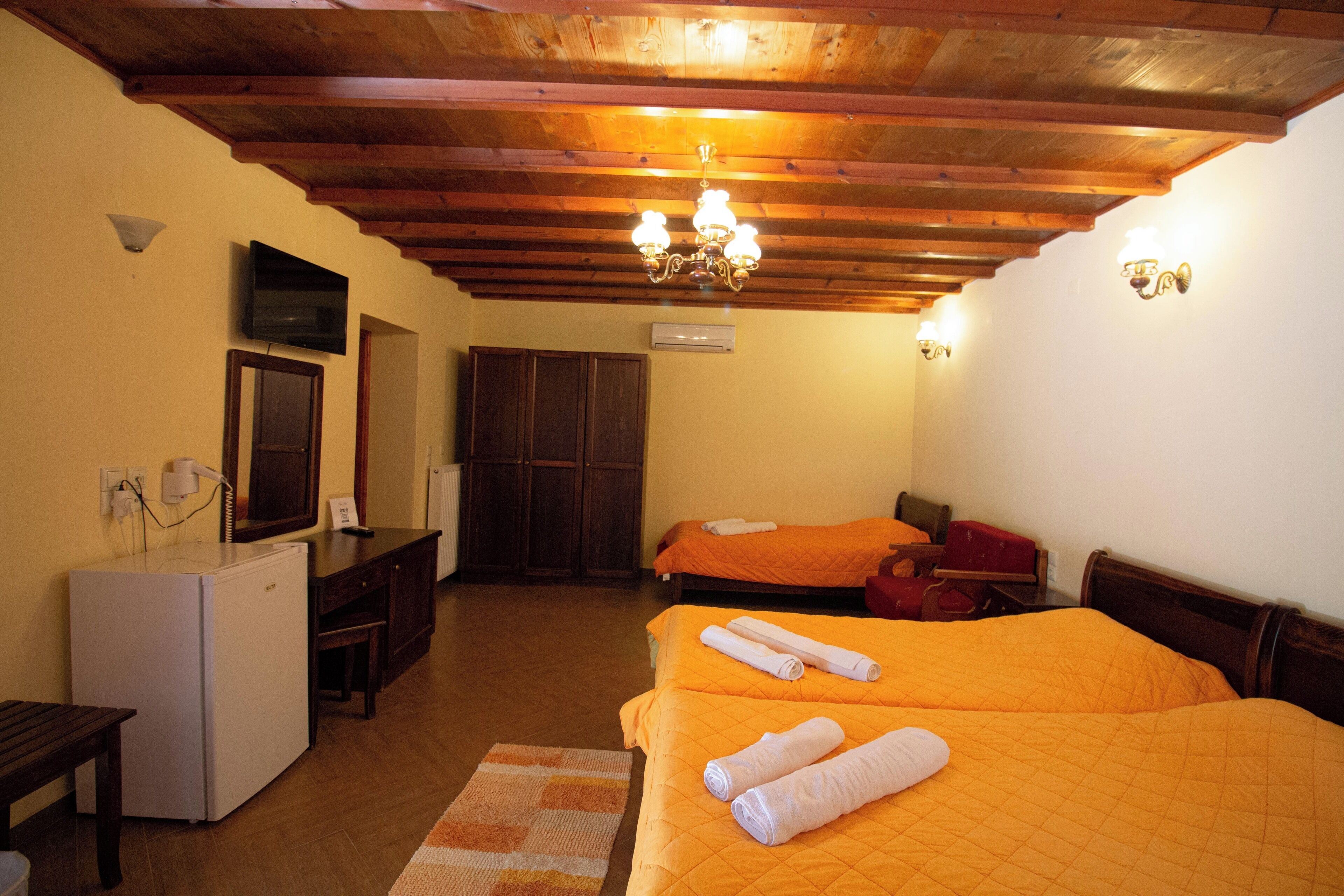 Camera d'albergo con due letti, un piccolo frigorifero, una scrivania e un soffitto in legno.