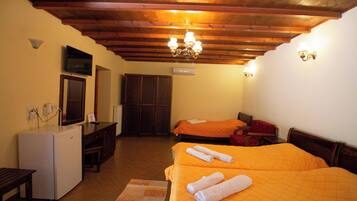 Camera d'albergo con due letti, un piccolo frigorifero, una scrivania e un soffitto in legno.