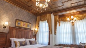 Un dormitorio amplio con una cama grande, techo de madera y un candelabro.