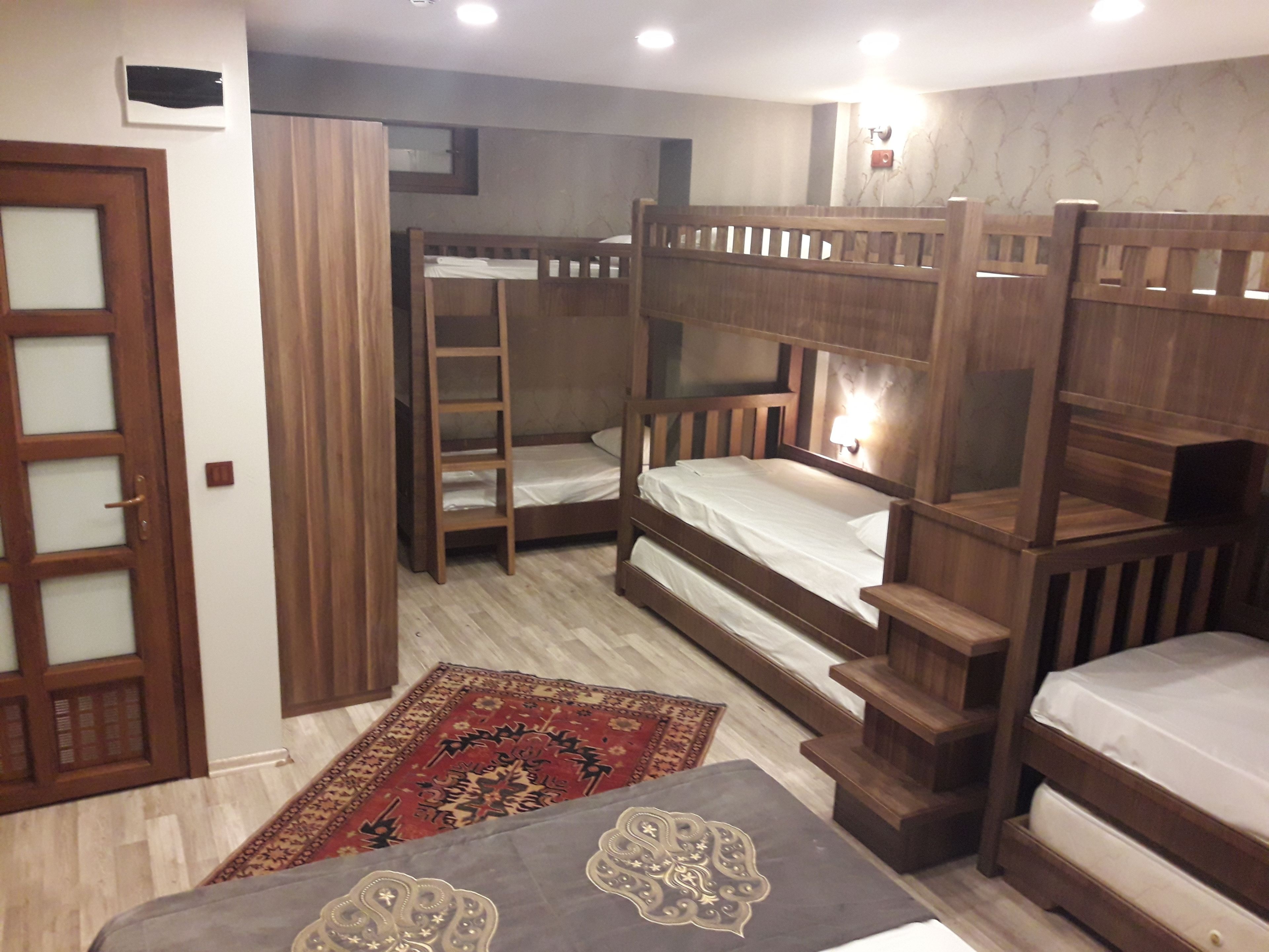 A room with bunk beds, a wooden door, a patterned rug, and a small table with a decorative item.