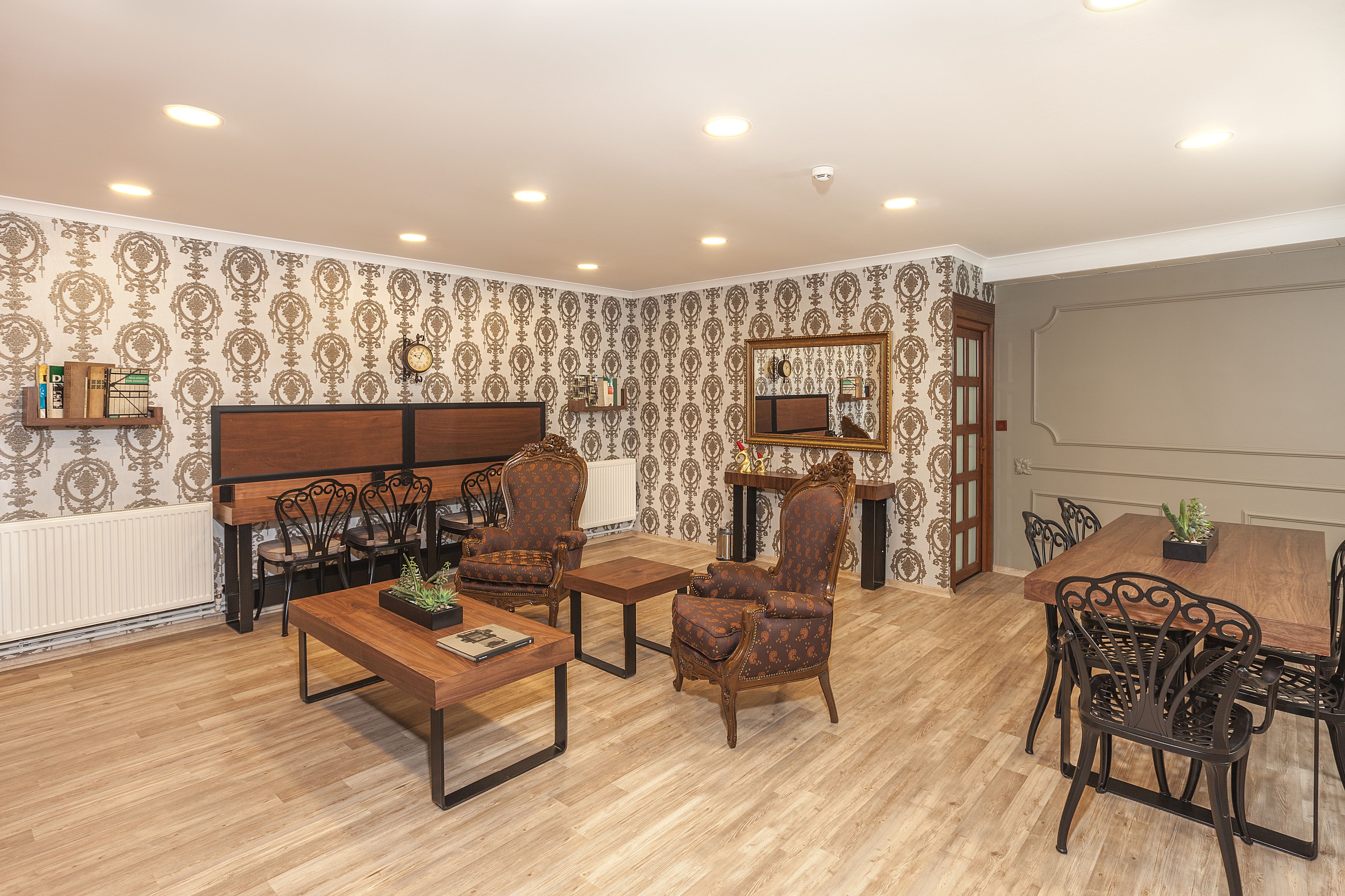 A dining area with a wooden table and chairs, a small side table, and a decorative mirror.