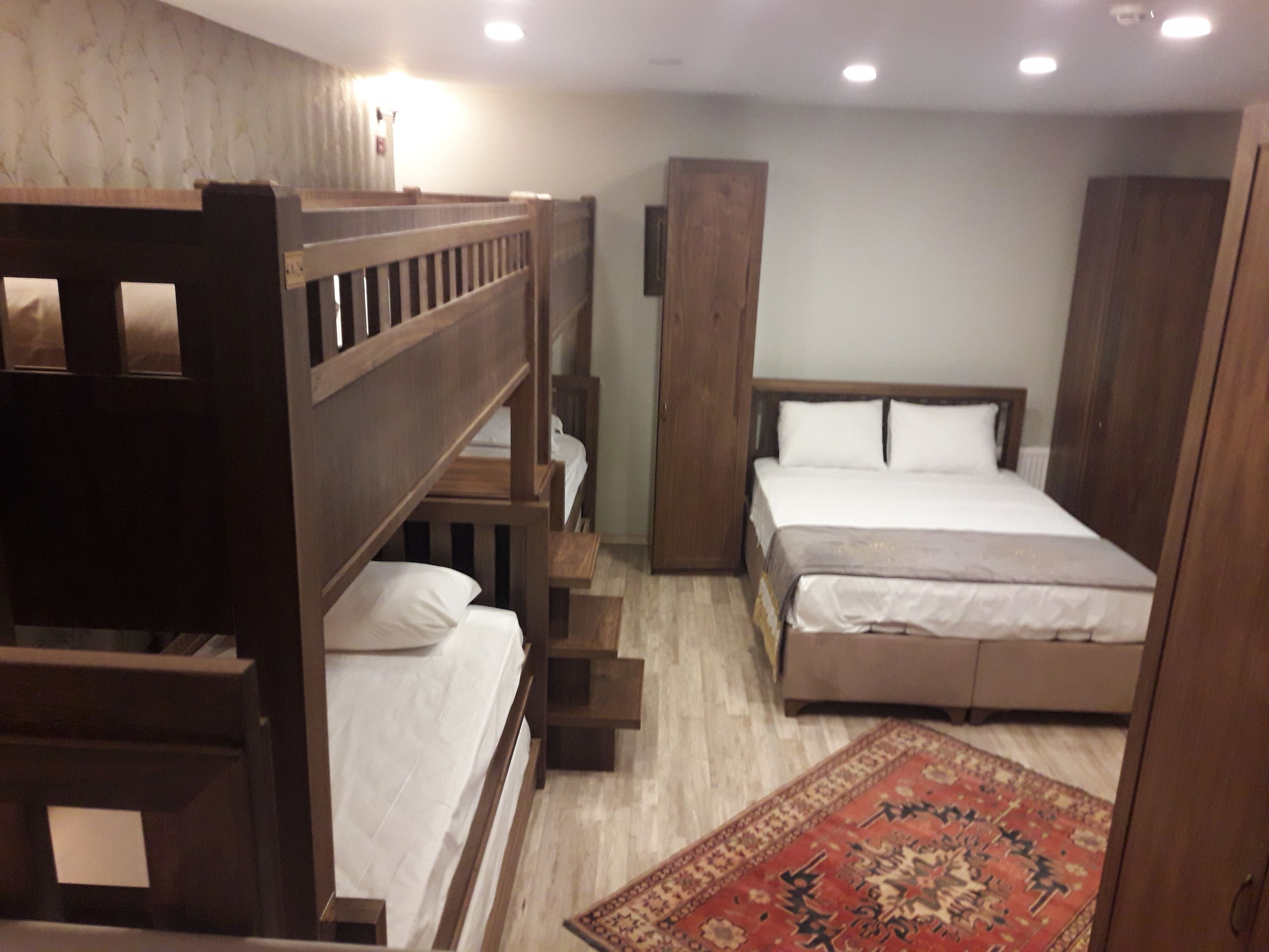 Un dormitorio con literas, una cama individual y un armario de madera.
