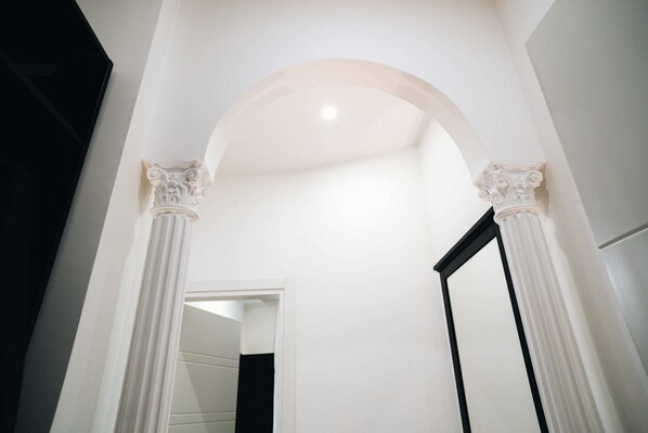 An arched doorway with white columns and a mirror on the right.