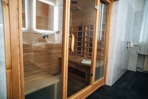 A sauna room with wooden walls and a glass door, a bench, and a towel rack.