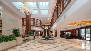 Eine geräumige Lobby mit einer zentralen Treppe, einem Brunnen und einer Rezeption.