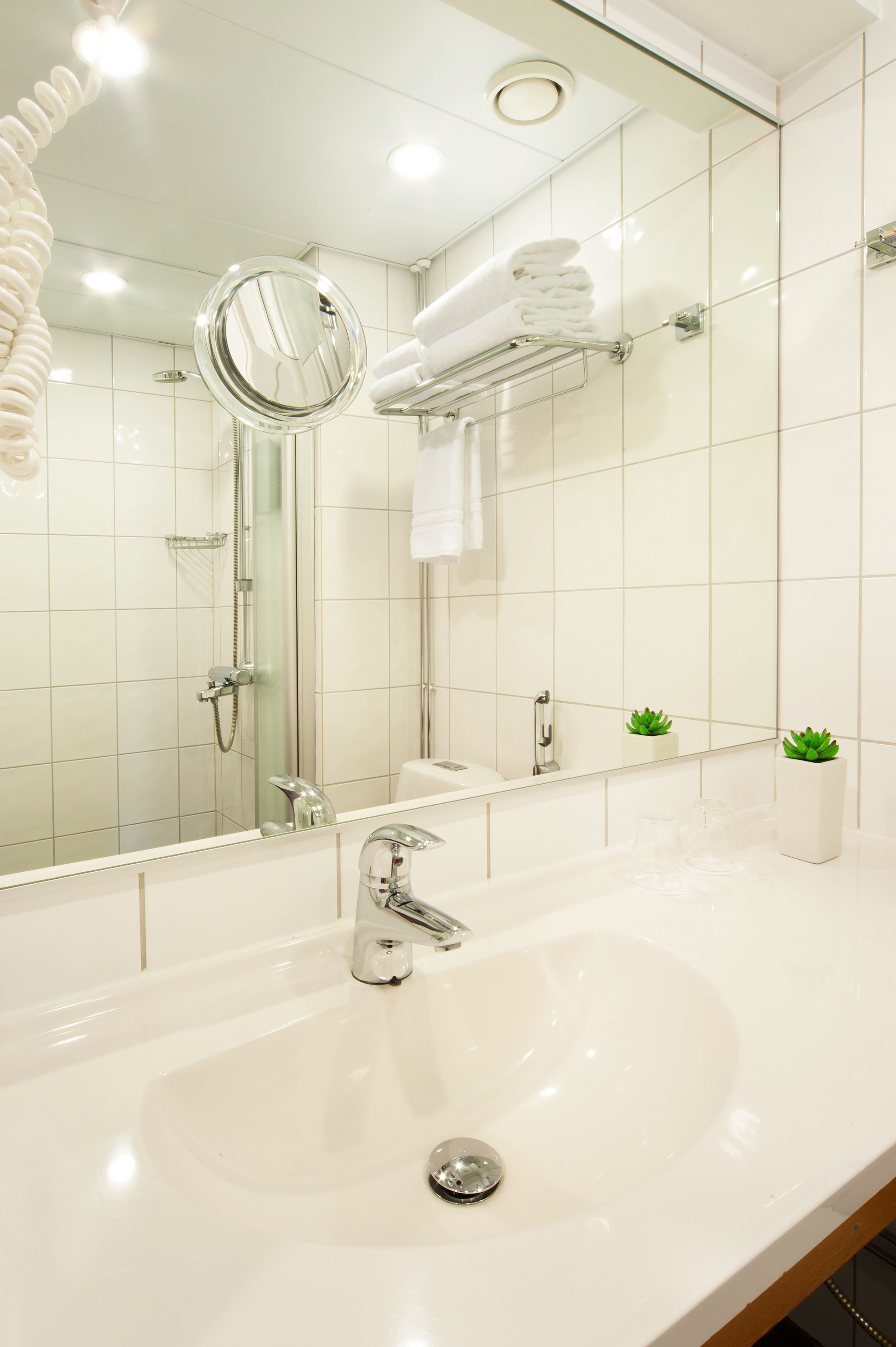 A modern bathroom with a large mirror, a sink, and a glass shower enclosure.