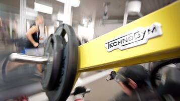 Een gele halterbank met het merk 'TECHNOGYM'.