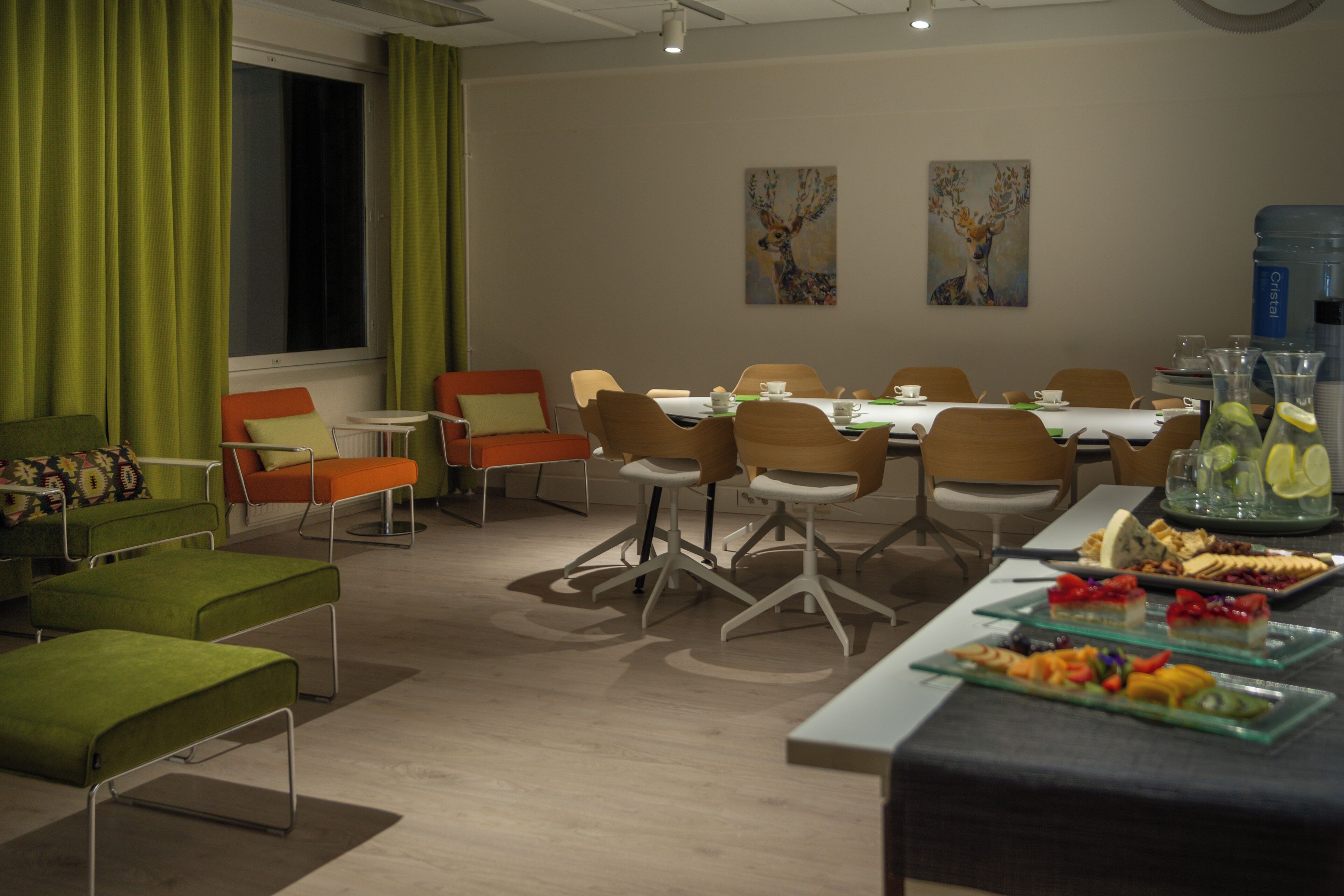 Una sala de conferencias moderna con una mesa redonda, sillas y una mesa de buffet con frutas y bebidas.