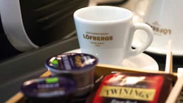 Eine weiße Kaffeetasse mit Aufschrift, eine kleine Dose und eine Packung Twinings Tee.