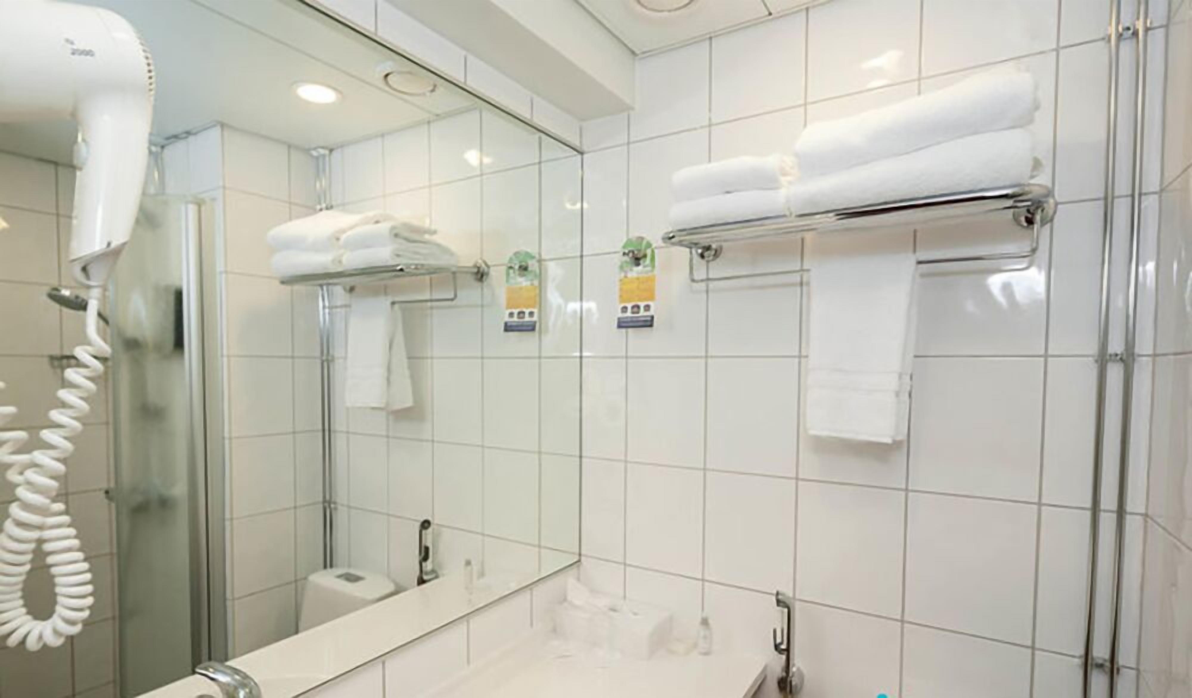 A modern bathroom with a glass shower enclosure, a hairdryer, and neatly arranged towels on a rack.