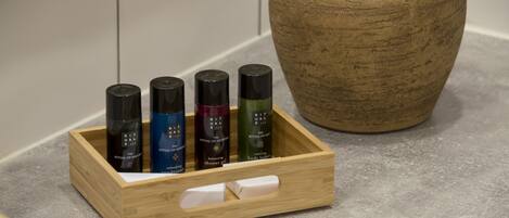 A wooden tray with four bottles of Rituals body lotion on a countertop next to a potted cactus.