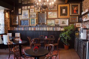 A cozy restaurant with wooden chairs and tables, a brick wall, and a variety of framed pictures on the wall. - Hotel loft (Samara)
