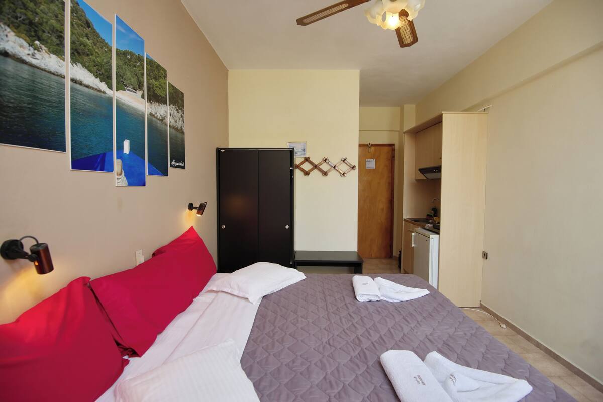 A hotel room with a bed, a wardrobe, a desk, and a view of the sea.