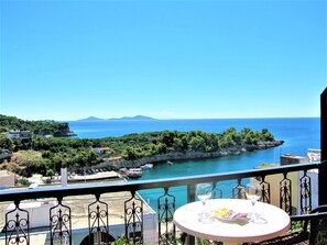 A balcony with a table, a view of the sea, and a distant island. - Gorgona Hotel (Alonissos)