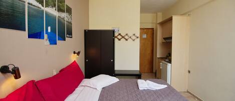 A hotel room with a bed, a wardrobe, a desk, and a bathroom.