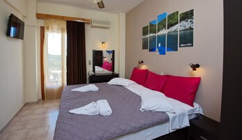 Habitación de hotel con una cama grande, televisor de pantalla plana, balcón con una silla y aire acondicionado instalado en la pared.