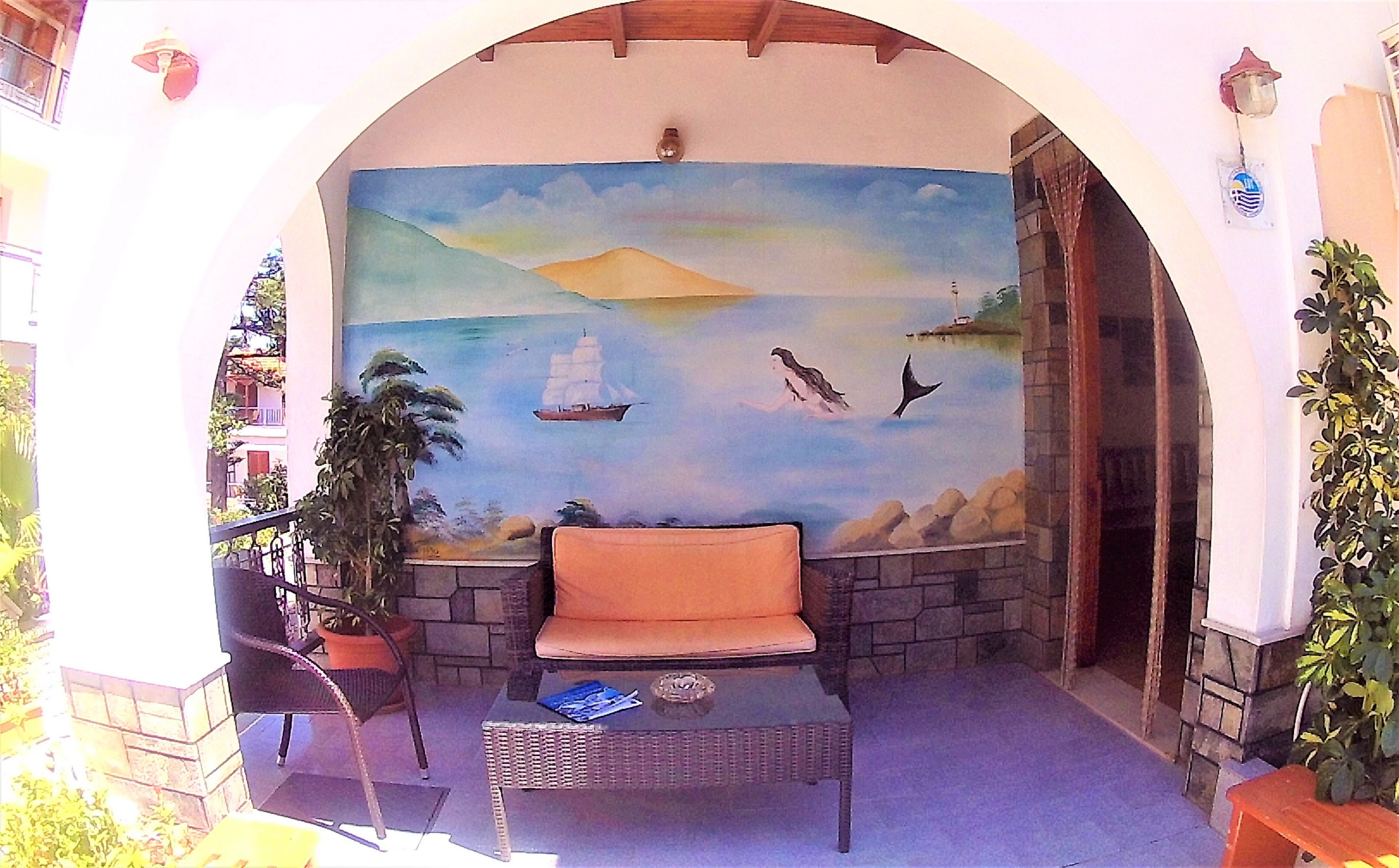 Un patio con un mural de paisaje marino, una silla de mimbre y una pequeña mesa.