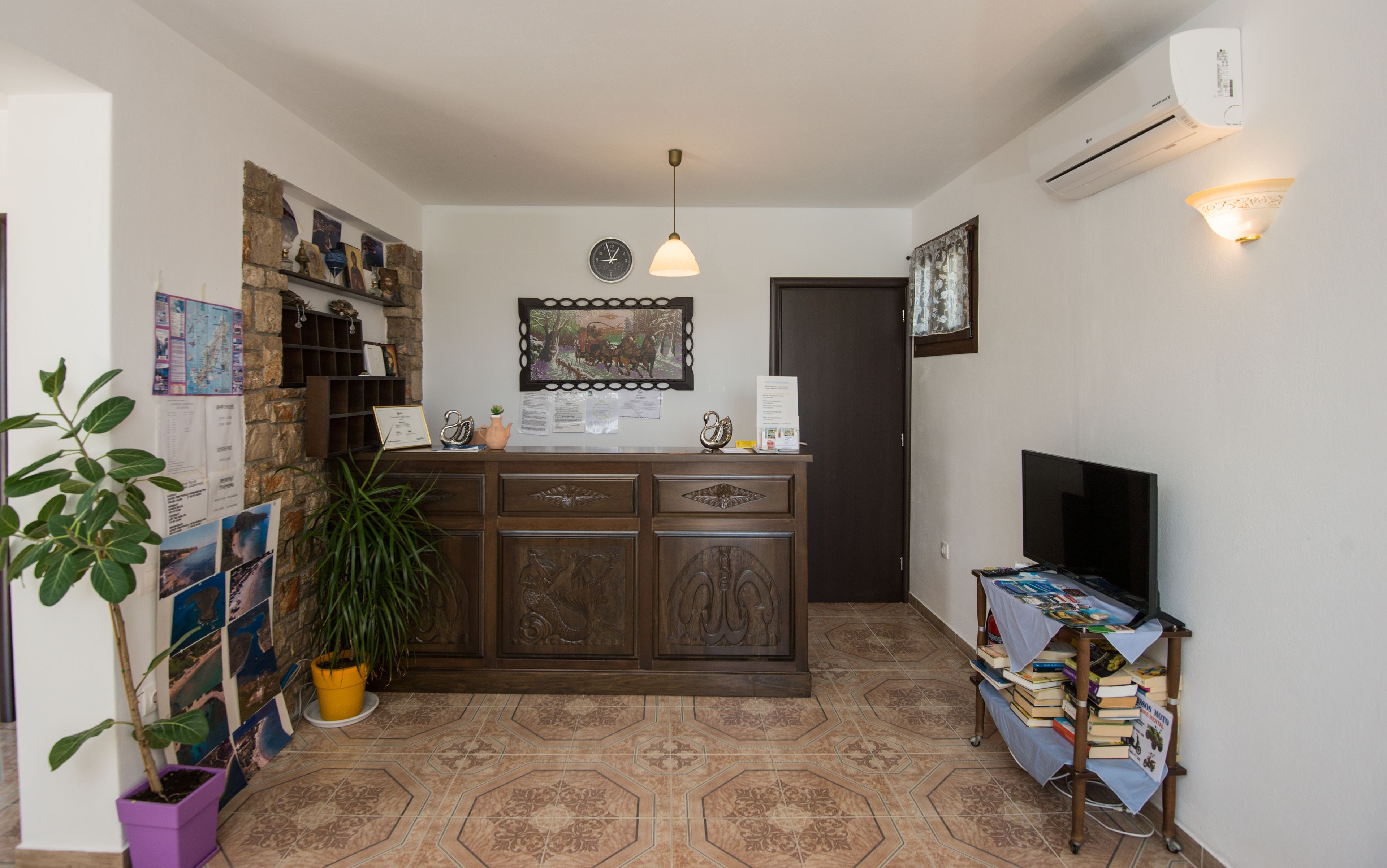 A small, cozy room with a wooden cabinet, a television, a potted plant, and a wall-mounted air conditioner.