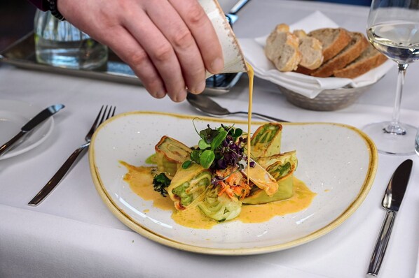 A plate of food being served with a sauce being poured over it.
