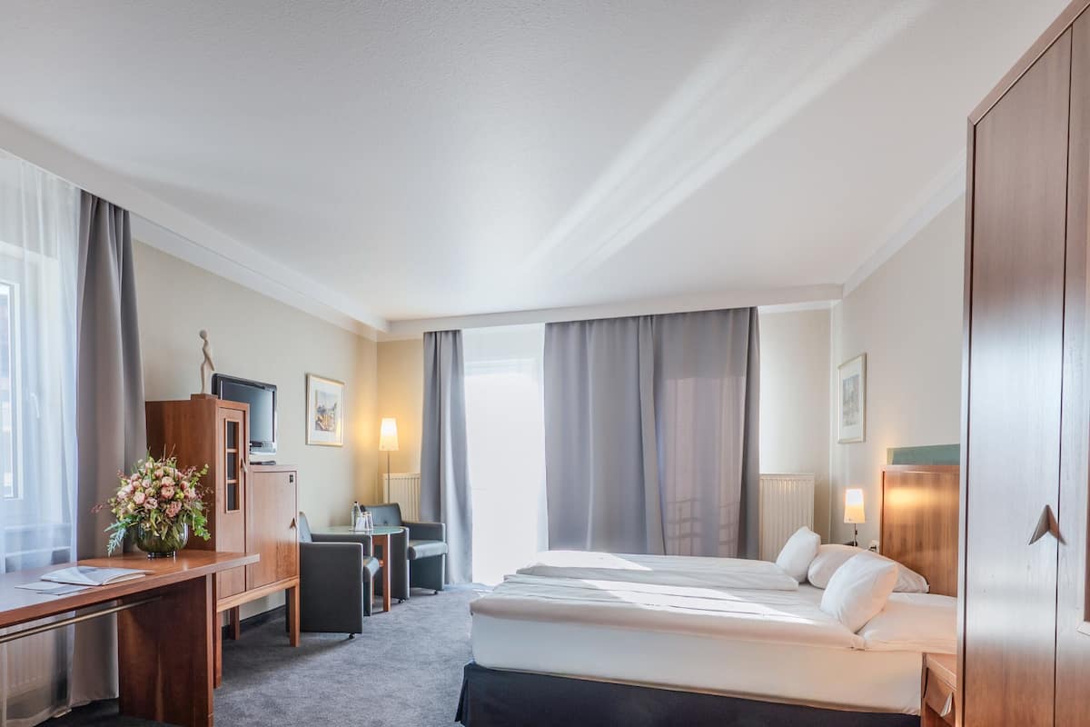 Una habitación de hotel con cama, escritorio, silla y armario.