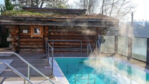 Una cabaña de madera con piscina, barandillas de metal y un respiradero de vapor.