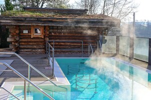 A log cabin with a pool, metal railings, and a steam vent.