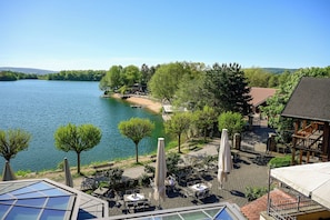 A lakeside view with outdoor seating, a boat dock, and a building with a sloped roof.
