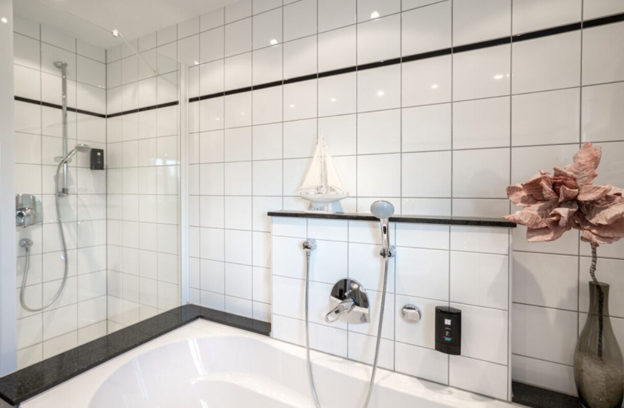 A modern bathroom with a bathtub, a shower area, and a wall-mounted control panel.