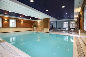Una piscina techada, una piscina al aire libre, sombrillas