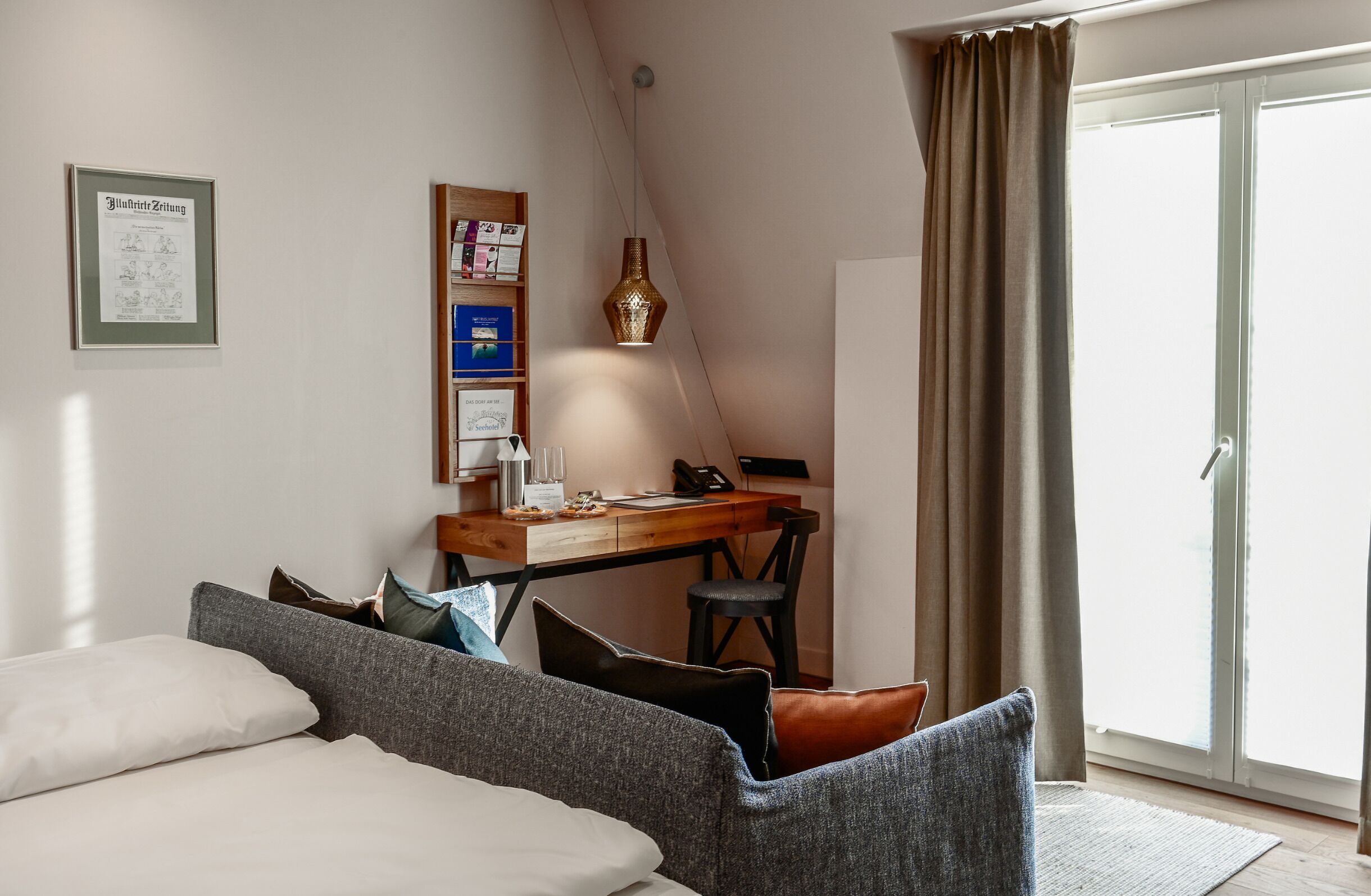 Een slaapkamer met een bed, een bureau, een stoel, een lamp en een schuifdeur.