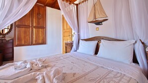 A bedroom with a wooden ceiling, a bed with white bedding, and a sailboat decoration on the wall. - Pelagos Villas (Alonissos)